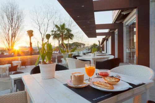 una mesa con desayuno y zumo de naranja en el balcón en Hotel Flamero, en Matalascañas