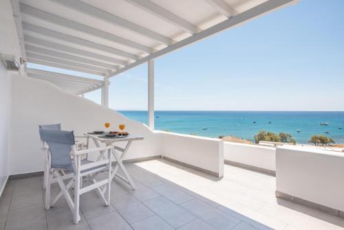 a balcony with a table and chairs and the ocean at Vista Del Mar Milos in Agia Kiriaki Beach