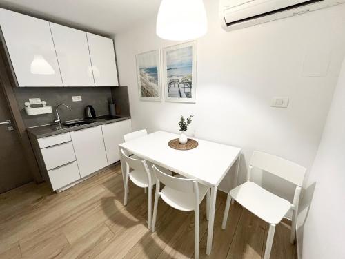 a kitchen and dining room with a white table and chairs at Casa Orange in Koper