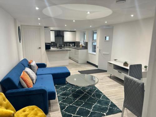 a living room with a blue couch and a kitchen at The Lucia Apartments II - 1 Bedroom Town Centre Apartment - Contractor Friendly - Free Parking - Full Kitchen - Washer Dryer - Spacious - Ideal for Work Stays in Huntingdon