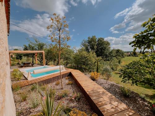 un jardin avec une piscine et une terrasse en bois dans l'établissement La Maison Des Pierres Blondes, à Orban