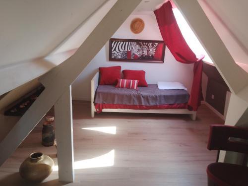 une chambre mansardée avec un lit avec des oreillers rouges dans l'établissement Maison Bord de Seine, à Belbeuf