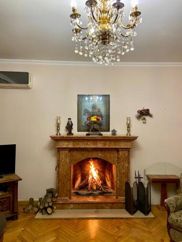 a living room with a fireplace with a chandelier at Villa Visteria with terrace in Batumi