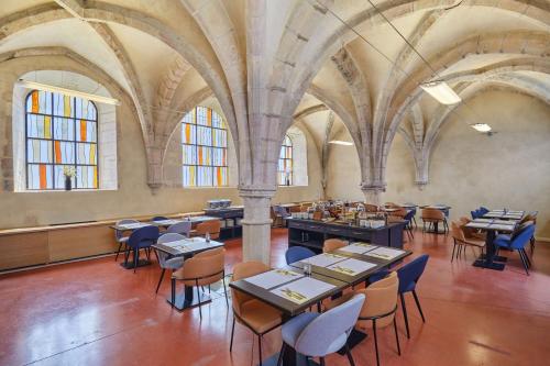 a dining room with tables and chairs in a building at Appart'hôtel Odalys City - Dijon Centre Les Cordeliers in Dijon