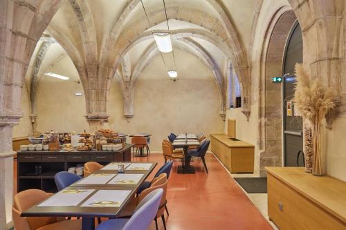 a restaurant with tables and chairs in a building at Appart'hôtel Odalys City - Dijon Centre Les Cordeliers in Dijon