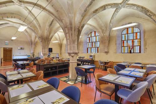 a restaurant with tables and chairs in a building at Appart'hôtel Odalys City - Dijon Centre Les Cordeliers in Dijon
