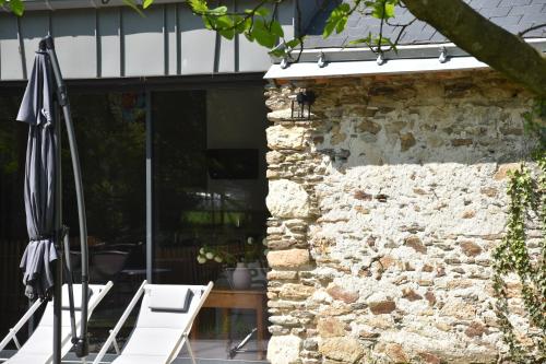 an outdoor patio with umbrellas and a stone wall at L'Escapade du Crezou in Nort-sur-Erdre