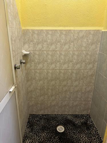 a bathroom with a shower with a black and white floor at Hotel Las Salinas in Zihuatanejo