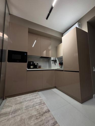 タシュケントにあるАренда квартиры #19 NRG U-Tower Rent an apartmentのタイルフロアの広いキッチン(ブラウンキャビネット付)