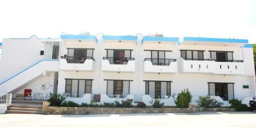 a white building with black windows and white chairs at Archodia Studios in Kefalos