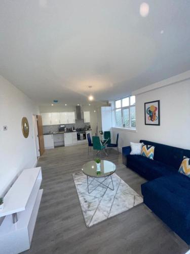 a living room with a blue couch and a table at 2 Bedroom Apartment - Flitwick - Contractor Friendly - Tourist Ready - Full Kitchen - WiFi - Smart TV - Sofa Bed - FREE Parking - Ideal for Short or Long Stays in Flitwick