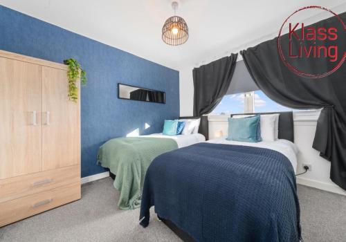 a bedroom with two beds and a blue wall at Orbiston House by Klass Living Bellshill in Bellshill