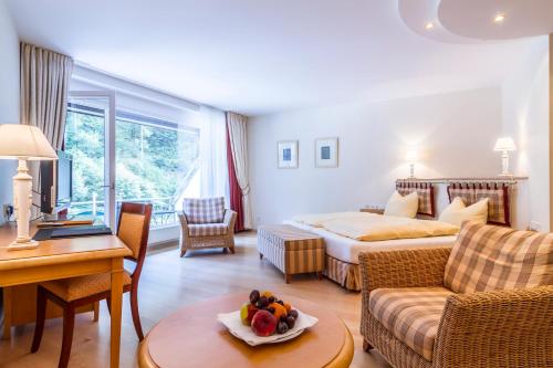 a hotel room with a bed and a table with a bowl of fruit at Waldhotel Bad Sulzburg in Sulzburg