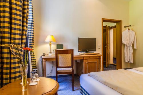 a hotel room with a bed and a desk with a television at Waldhotel Bad Sulzburg in Sulzburg
