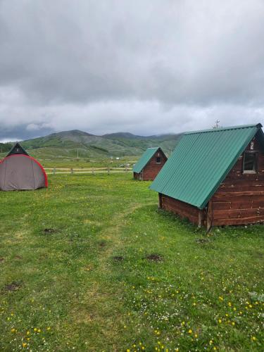 two barns and a tent in a field at Guest House Ethno Village Milogora in Pluzine