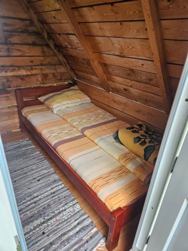 a bed in a wooden cabin with wooden ceilings at Guest House Ethno Village Milogora in Pluzine