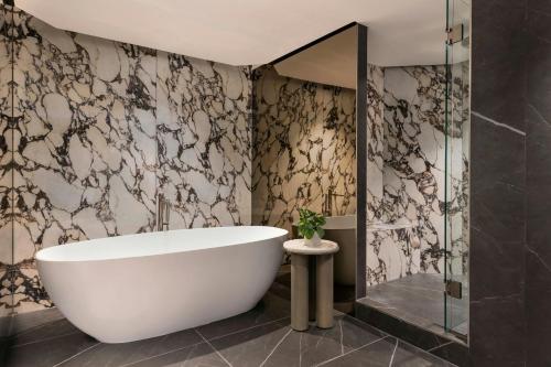 a bathroom with a tub and a glass shower at JW Marriott Auckland in Auckland