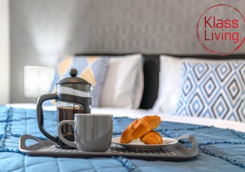 a breakfast tray with croissants and coffee on a bed at Sanderson Apartment by Klass Living Uddingston in Uddingston