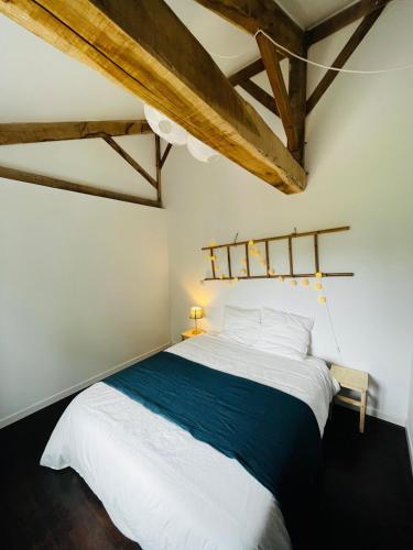 une chambre avec un grand lit dans une pièce avec des plafonds en bois dans l'établissement Corps de ferme Gers, à Saint-Blancard