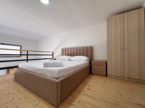 Un dormitorio con una cama grande y un armario de madera. en Apartamente me qera Golem, en Golem
