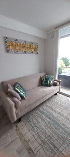 a brown couch in a living room with a window at Departamento nuevo 2D 1B cerca del Mall in Puerto Montt