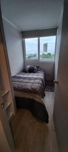 a bedroom with a bed in a room with a window at Departamento nuevo 2D 1B cerca del Mall in Puerto Montt