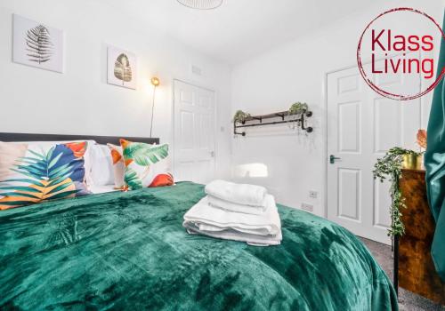 a bedroom with a green bed with towels on it at Uddingston Apartment by Klass Living in Uddingston
