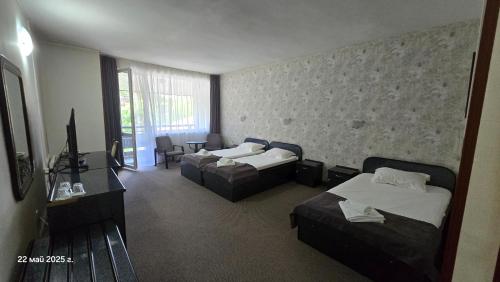 a hotel room with two beds and a television at Хотел Тото Шанс in Velingrad