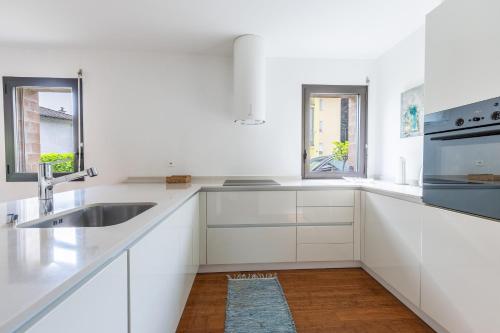 a white kitchen with white cabinets and a sink at Feel like home, close to Verzasca, Tenero, Locarno in Gordola