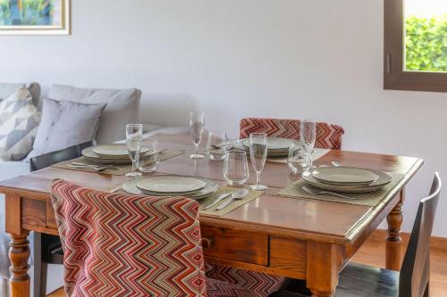a wooden table with plates and wine glasses on it at Feel like home, close to Verzasca, Tenero, Locarno in Gordola