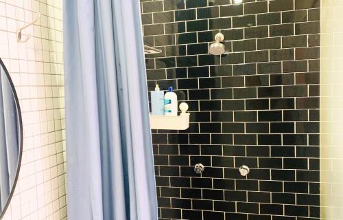 a shower with a black tiled wall with a shelf at Beguest Centro Concerts & Events in Mexico City
