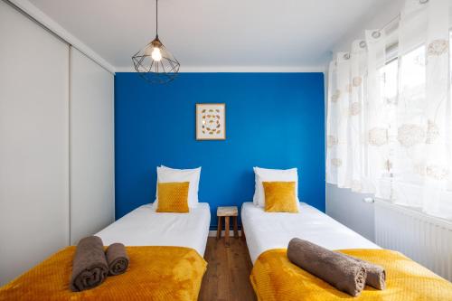 - 2 lits dans une chambre avec un mur bleu dans l'établissement Appartement Ginkgo au Cœur de L'Alsace - Sélestat - 4 à 6 personnes, à Sélestat