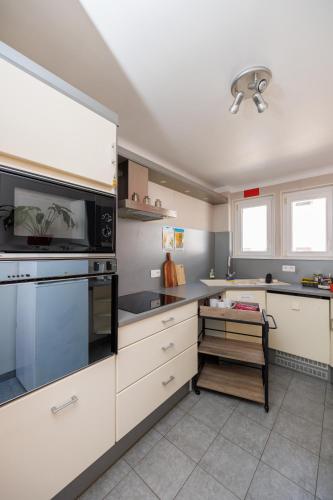 une cuisine avec des armoires blanches et un four à plaques de cuisson dans l'établissement Appartement Ginkgo au Cœur de L'Alsace - Sélestat - 4 à 6 personnes, à Sélestat