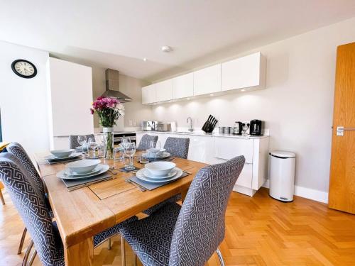 a dining room table with chairs and a kitchen at Beautiful Apartment In The Heart of Chelmsford in Chelmsford