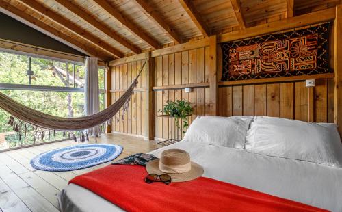a bedroom with a bed with a hat and a hammock at Moradas do Vale Praia do Rosa in Praia do Rosa
