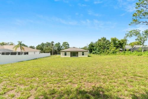 a large yard with a house and a white fence at Springhill Retreat! 3 bed, 2 Bath! in Spring Hill