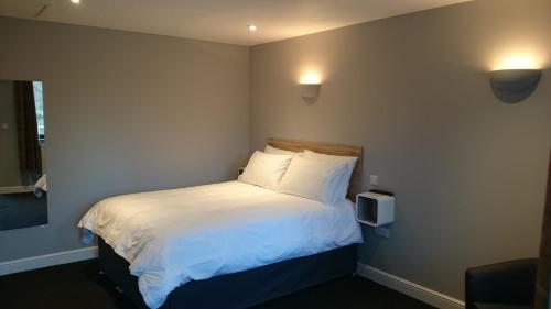 una camera da letto con letto, lenzuola e cuscini bianchi di Woodland Waters a Ancaster