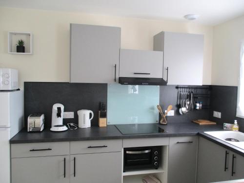 une cuisine avec des armoires blanches et un comptoir noir dans l'établissement Résidence les écluses, à Soulac-sur-Mer