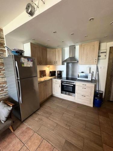 une cuisine avec un réfrigérateur en acier inoxydable et des armoires en bois dans l'établissement Résidence La Plage La Maisonnette - Joli T2 avec jardin avec un accès direct a la mer MAE-1923, aux Lecques