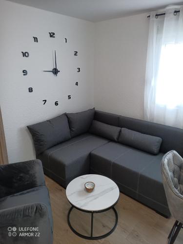 a living room with a couch and a clock on the wall at Apartmani Gaga in Tivat