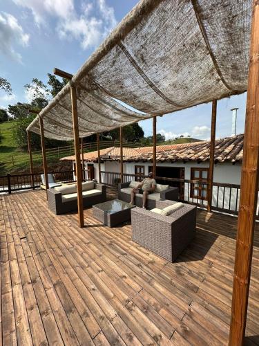 acovered deck with couches and chairs on a wooden deck at Hotel Cacaobetulia in Maceo