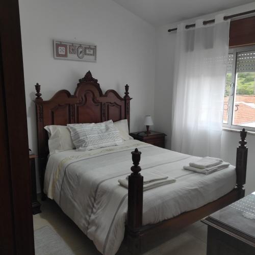 a bedroom with a large bed with a wooden headboard at Casa Furt@do in Burgau