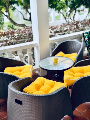a table with yellow cushioned chairs and a table with a cup on it at HCEAS villa is 5 min fr. airport & to the beaches in Bon Accord
