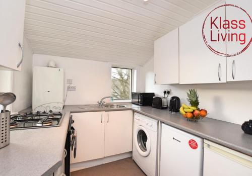 a kitchen with white cabinets and a washing machine at Whifflet Apartment by Klass Living Coatbridge in Coatbridge