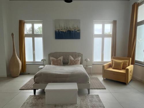 a bedroom with a bed and a chair and windows at Ferienwohnung Villa Bismarck mit Sauna und Whirlpool in Görlitz