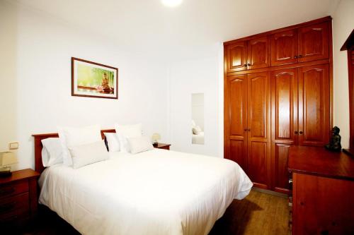 a bedroom with a white bed and a wooden cabinet at Las Cascadas Puerto de Mogán II in Puerto de Mogán