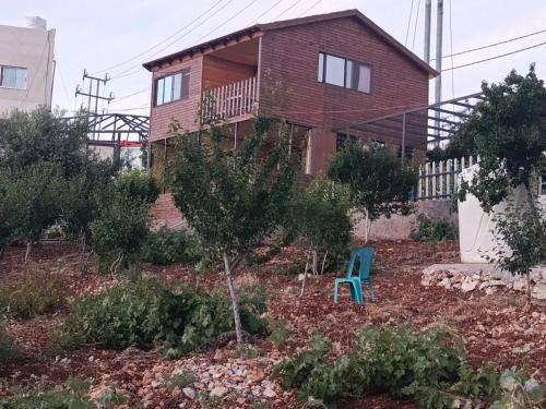 a house with a blue chair in a garden at أكواخ وشقق عبين السياحيه in ‘Ibbīn