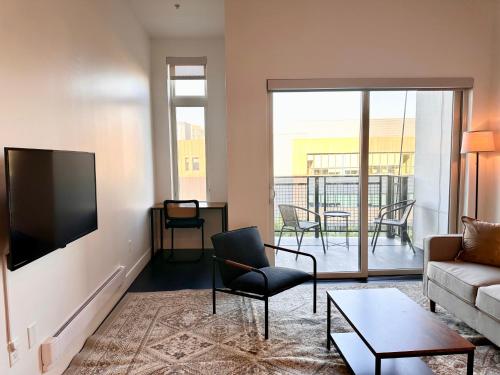 a living room with a couch and a flat screen tv at Modern Studio Apt with Skywalk to Fiserv, Rooftop, and Parking in Milwaukee