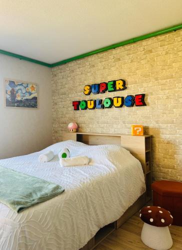 une chambre avec un lit avec un panneau de super-héros sur le mur dans l'établissement Rétro Gaming Universe, Escape game & Gameroom, à Aucamville
