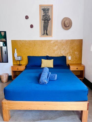 a bed with a blue blanket and two pillows on it at Palmar la Punta 10 AC Starlink 2min walk to beach in Brisas de Zicatela